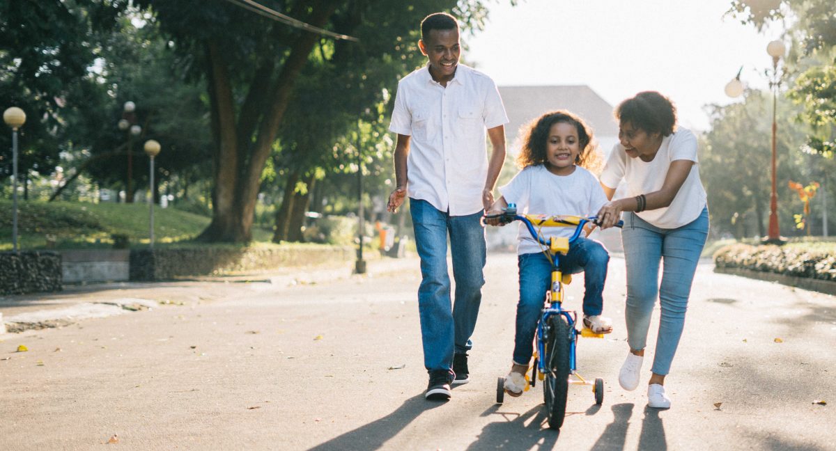 Man, woman and child on bike with training wheels.